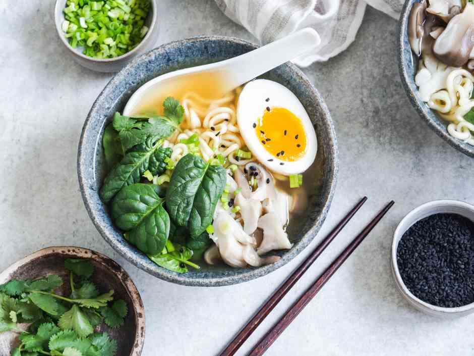 Wegetariańskie Miso Ramen z grzybami surowy szpinak i gotowane jajko w niebieskiej misce na szarym stole